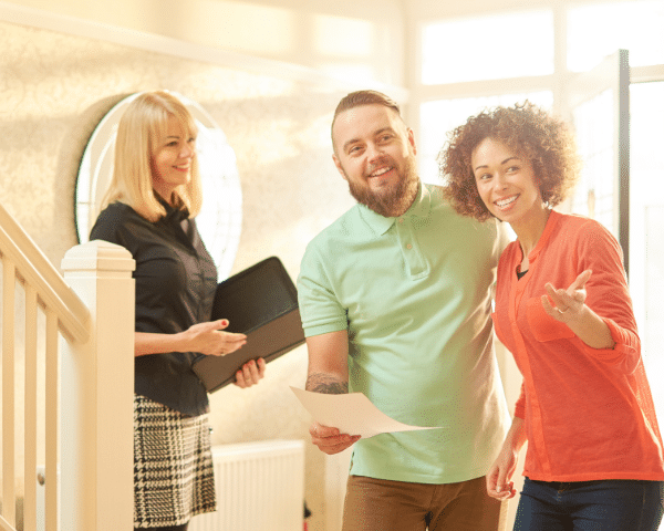 couple and realtor happily looking around a home