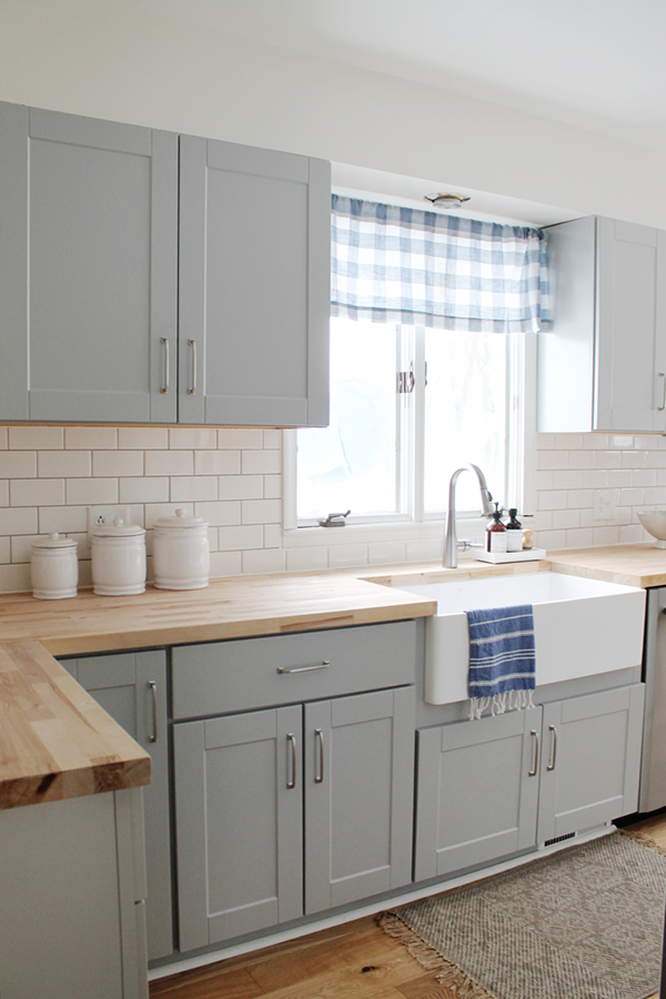Light gray kitchen with beech wood countertop and pops of blue accents