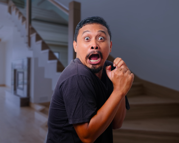 man looking scared inside a creepy house