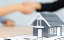 miniature house with people shaking hands in the background