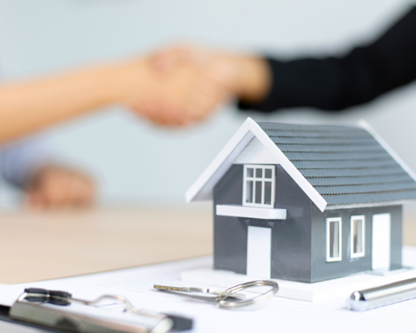 miniature house with people shaking hands in the background