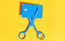 blue credit card about to be cut with blue scissors on a yellow background