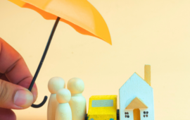 mini wooden figurines of an umbrella over people, car and house