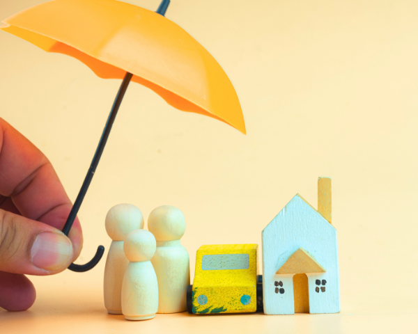 mini wooden figurines of an umbrella over people, car and house