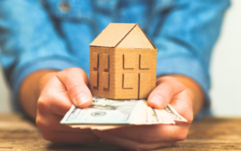 person holding cash with figure of a house on top