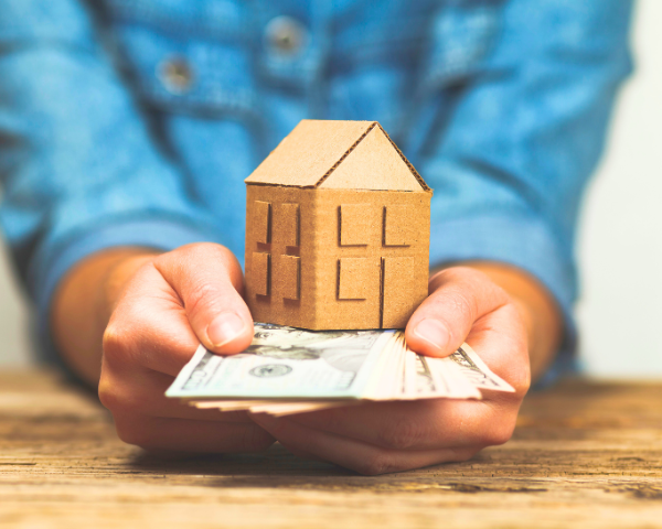 person holding cash with figure of a house on top