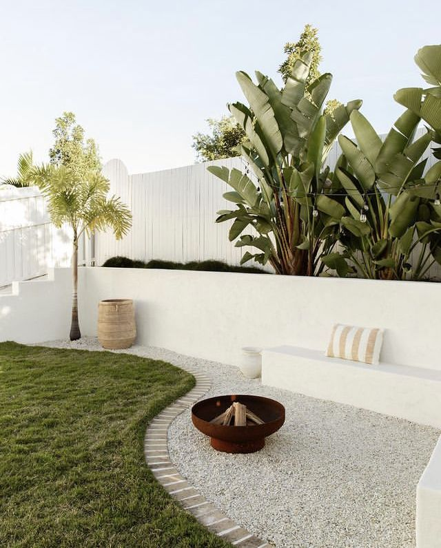 Beautiful landscape wtih fire pit, tall plants in the perimeter of the property