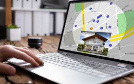 A person uses a laptop displaying a real estate map with blue and orange location markers. An inset photo of a house shows a $600,000 price tag