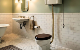 Vintage-style bathroom with a clawfoot tub, pedestal sink, and high-tank toilet. White subway tiles, hexagonal floor tiles, and soft green walls.