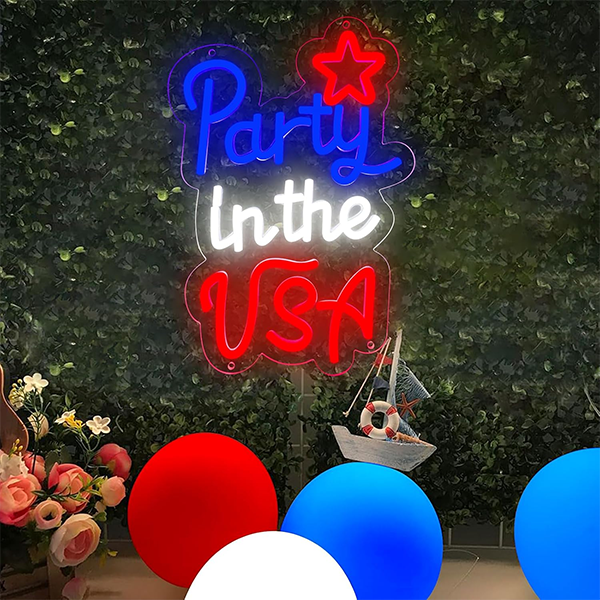 Neon sign reading Party in the USA in blue, white, and red against a leafy backdrop. Red, white, and blue balloons and flowers create a festive vibe. Neon sign reading Party in the USA in blue, white, and red against a leafy backdrop. Red, white, and blue balloons and flowers create a festive vibe.