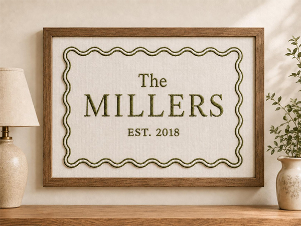 Framed wood sign reading “The Millers, Est. 2018,” with a vintage wavy border, displayed in a warm, cozy living room beside plants and lamps.